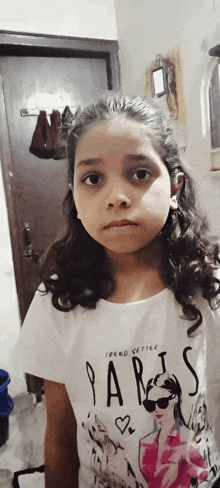 a young girl wearing a white shirt with the word paris on it