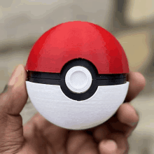 a person is holding a red white and black poke ball