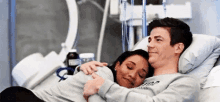 a man and a woman are laying in a hospital bed .