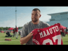 a man is holding a red jersey with the number 27 on it .