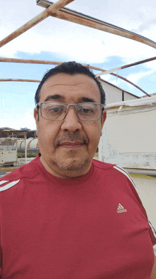 a man wearing glasses and an adidas shirt