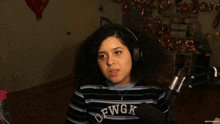 a woman wearing headphones and a striped shirt that says dfwgk