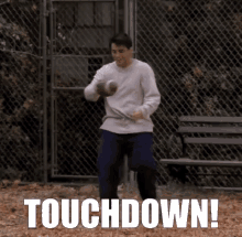 a man holding a football in front of a chain link fence with the words touchdown written on the bottom