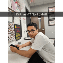 a young man sitting at a desk with the words did i ask no i did n't written above him