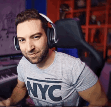 a man wearing headphones and a nyc shirt is smiling