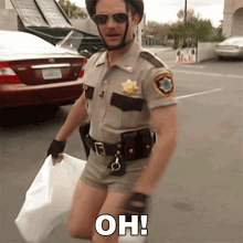 a man in a sheriff 's uniform is kneeling down and holding a white bag with the words oh written on it