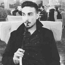 a man with a beard is smoking a hookah in a black and white photo