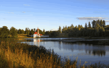 a small white house with a red roof sits on a small island in the middle of a lake