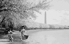 a black and white photo of two women walking by a body of water