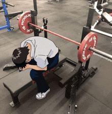 a man is sitting on a bench with a barbell on it that says rogue on it