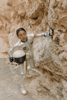 a woman in a nasa outfit holds a helmet