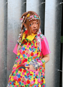 a woman wearing a colorful dress with smiley faces on it holds a remote control