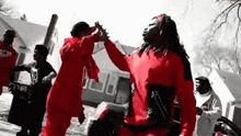 a group of men in red hoodies are standing next to each other .