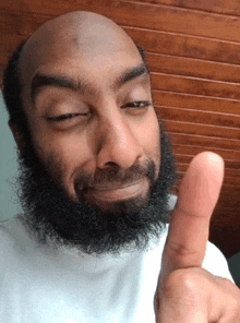 a man with a beard is making a funny face and giving a thumbs up