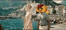 a man and a woman walking by the water with a yellow box on their head