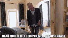 a man with a cane is standing in a bedroom with a caption that says daar moet je mee stoppen