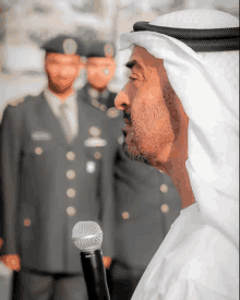 a man speaking into a shure microphone in front of two soldiers