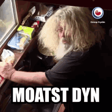 a man with long blonde hair and a beard is cooking in a kitchen with the words moatst dyn below him