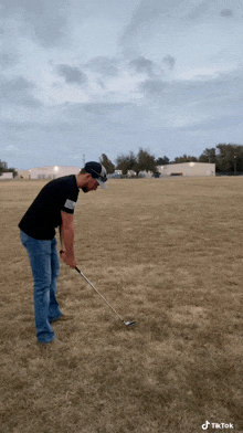 a man is swinging a golf club in a field with a tiktok watermark on the bottom