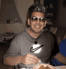 a man wearing sunglasses and a nike shirt is sitting at a table