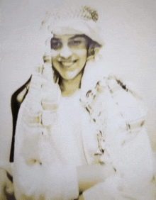 a black and white photo of a smiling woman wearing a hat