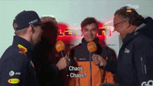 a man in an orange jacket is being interviewed by a group of men