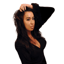 a woman in a black top has her hand on her head