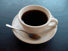 a cup of coffee is on a saucer with a spoon