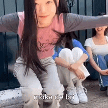 a woman is sitting on the ground with her arms outstretched and the words moka de bri written on the ground .