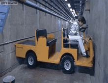 a person is driving a small yellow vehicle in a tunnel .