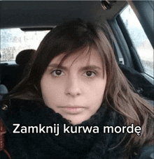 a woman sitting in a car with the words zamknij kurwa morde written below her