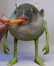 a person is holding a carrot in the mouth of a monster fish .