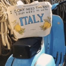 a blue scooter with a sign on the back that says i do n't need therapy i just need to go to italy