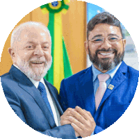 two men shaking hands in front of a flag and smiling