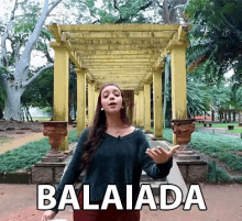 a woman in a green sweater stands in front of a pergola with the word balaiada written on the bottom