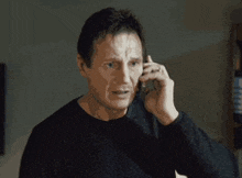 a man in a black sweater is talking on his cell phone