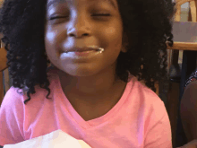 a little girl in a pink shirt has a white swirl on her mouth