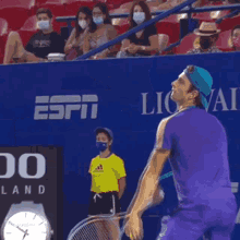 a man in a purple shirt is serving a tennis ball in front of a sign that says rado switzerland