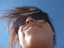 a woman wearing sunglasses is looking up at the sky