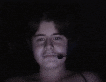 a man wearing headphones and a microphone looks at the camera in a dark room