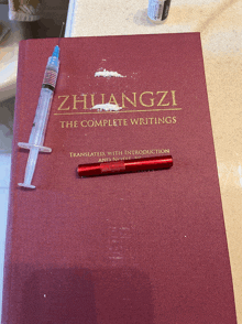 a book titled zhuangzi the complete writings with a syringe and pen on it