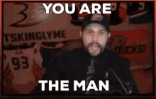 a man in front of a sign that says ' you are the man ' on it