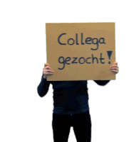 a man holds up a sign that says collega gezocht