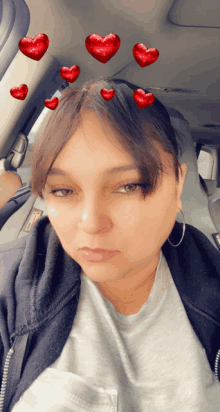 a woman sitting in a car with red hearts on her head