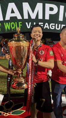 a man in a red shirt is holding a trophy that says vietnam professional football