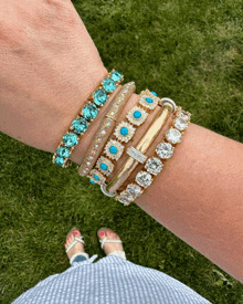 a woman wearing a stack of bracelets with turquoise and diamonds