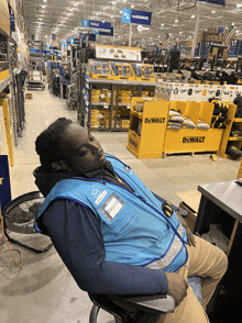 a man is sleeping in a chair in front of a dewalt display