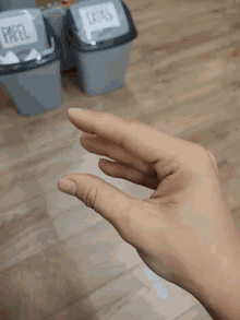 a person 's hand is reaching for a trash can that says paper