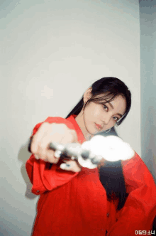 a woman in a red shirt is holding a gun in her hand