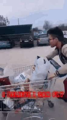 a man pushing a shopping cart full of groceries with the words " i believe i can fly " written on it